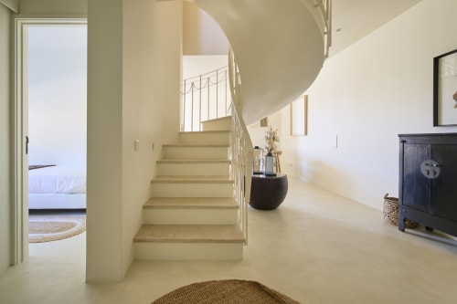 Modern spiral staircase in Casa Redonda T3 apartment at Aroeira villa with cream walls and metal railings