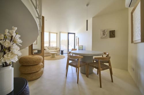 Modern dining area in Casa Redonda apartment at Aroeira BnB with round table, woven chairs, and garden view doors