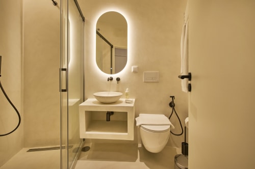 Modern bathroom at Casa Redonda by Villas Aura in Aroeira with illuminated oval mirror, vessel sink, and rainfall shower
