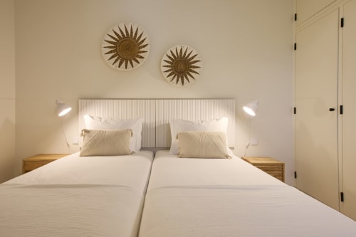 Modern twin bedroom at Casa Redonda by Villas Aura in Aroeira with dual beds, decorative wall art, and wooden nightstands