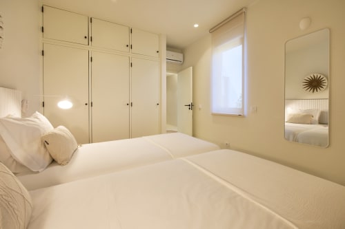 Modern bedroom at Casa Redonda by Villas Aura in Aroeira with twin beds, cream bedding, and mirrored wardrobe