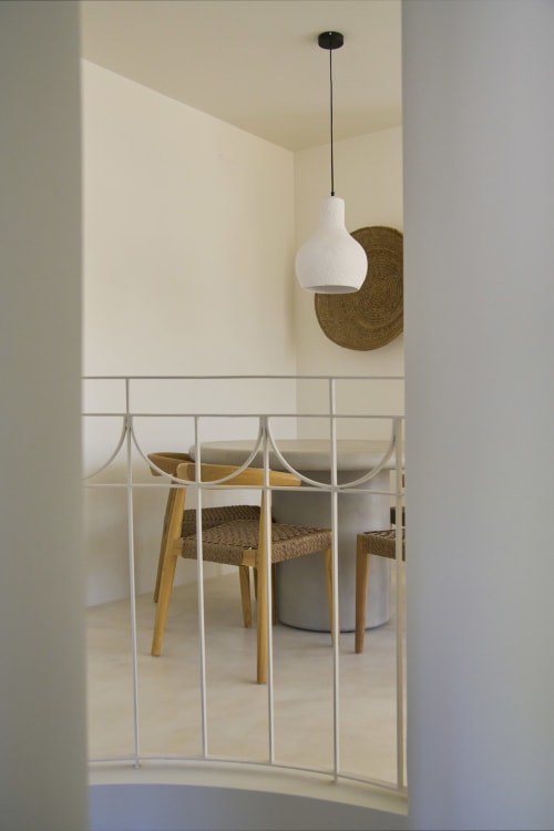 Modern dining area at Casa Redonda with white pendant light, metal bed frame, woven chairs, and neutral decor in Aroeira