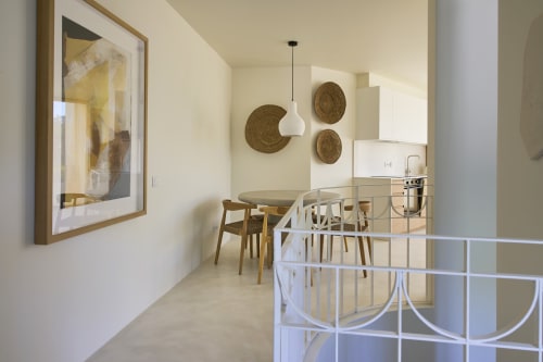 Modern dining area in Casa Redonda apartment, Aroeira with wooden table, woven basket wall art, and kitchen view