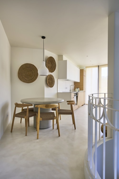 Modern open-plan kitchen and dining area with round table, wooden chairs, woven wall art at Casa Redonda, Aroeira