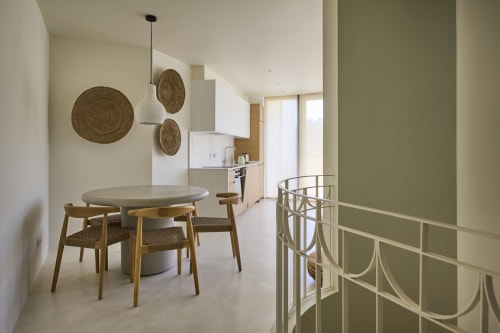 Modern dining area in Casa Redonda apartment at Aroeira with round table, wooden chairs, and woven wall décor