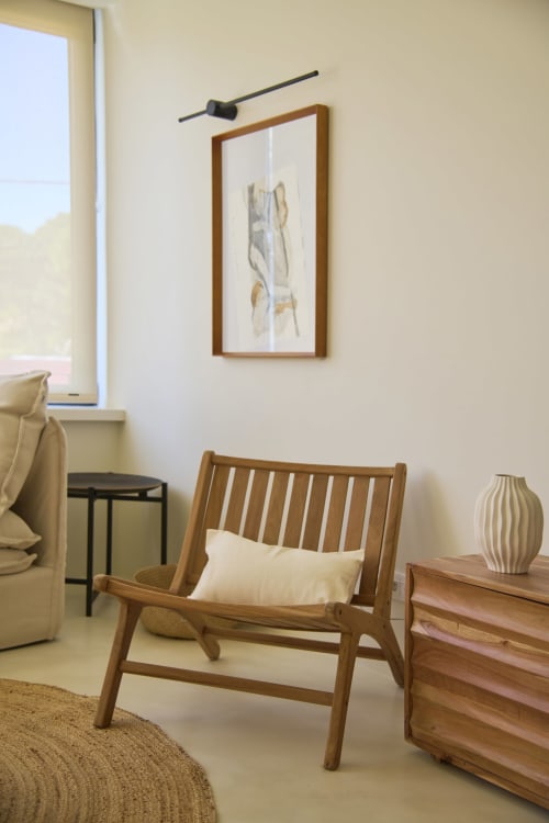 Modern living room at Casa Redonda, Aroeira with wooden chair, framed artwork, and minimalist décor