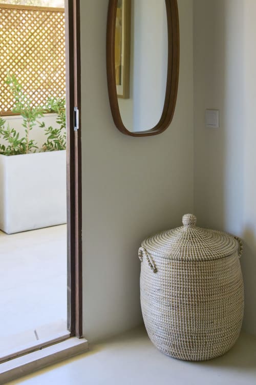 Modern entryway at Casa Redonda with woven basket, round mirror, and potted plants near glass door in Aroeira