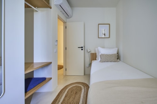 Modern bedroom at Casa Redonda by Villas Aura in Aroeira with single bed, wooden shelving, and air conditioning