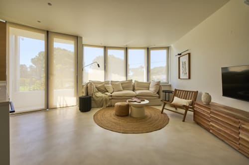 Modern living room at Casa Redonda in Aroeira with beige seating, round natural fiber rug, wooden furniture, and panoramic