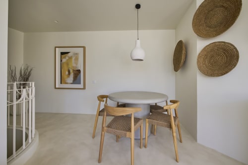 Modern dining area in Casa Redonda apartment with round white table, wooden chairs, and coastal décor at Aroeira villa.