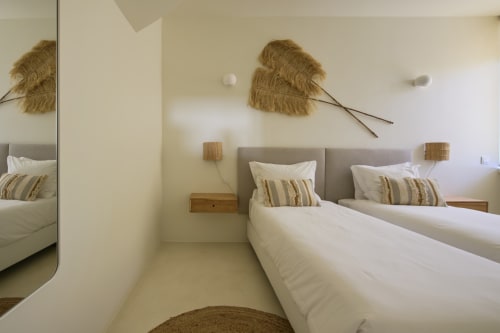 Modern bedroom at Casa Redonda by Villas Aura in Aroeira, Portugal with twin beds, neutral decor, and natural wall accents