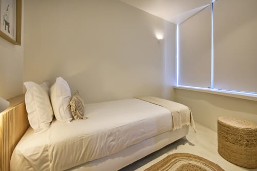 Bright minimalist bedroom at Casa Redonda, Aroeira with white bed, natural linens, and large window in Portuguese villa