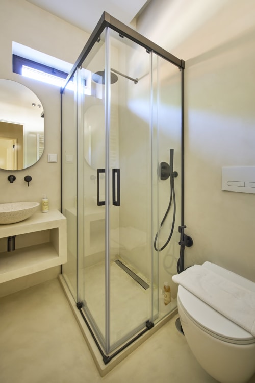 Modern bathroom with glass shower enclosure, sink, toilet and black fixtures at Casa Redonda, Aroeira