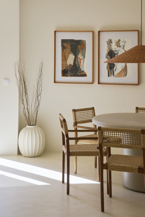 Modern dining area at Casa Redonda with woven chairs, round table, framed artwork, and white vase with branches