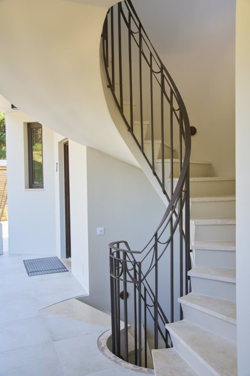 Modern spiral staircase with black metal railing in Casa Redonda apartment at Aroeira villa resort, Portugal