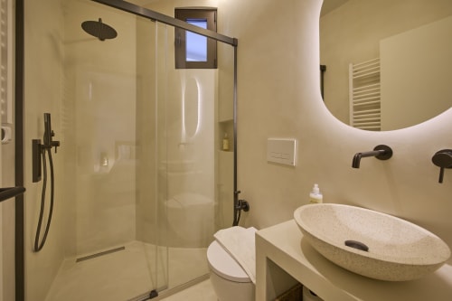 Modern bathroom with stone vessel sink, rainfall shower, and heated mirror at Casa Redonda by Villas Aura in Aroeira,