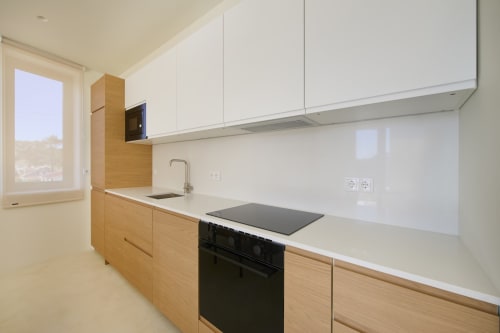 Modern kitchen in Casa Redonda apartment, Aroeira with white cabinetry, wood lower units, and black cooktop