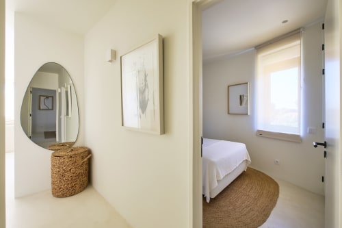 Modern bedroom at Casa Redonda by Villas Aura in Aroeira with oval mirror, woven basket, and white bedding