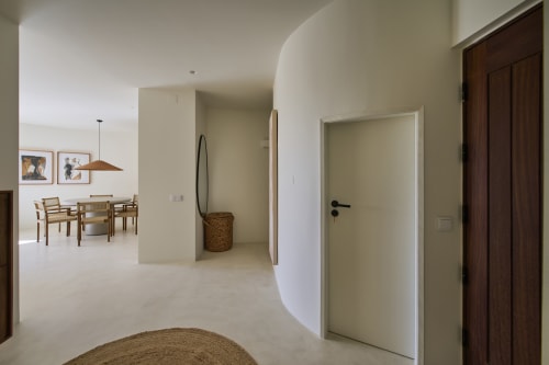 Modern apartment hallway at Casa Redonda, Aroeira with curved white walls, wooden doors, and woven basket decor