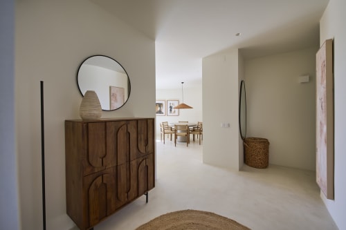 Modern apartment entryway at Casa Redonda, Aroeira with wooden cabinet, round mirror, and view to dining area
