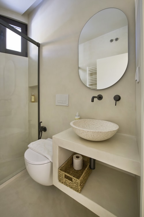 Modern bathroom in Casa Redonda apartment, Aroeira with round mirror, stone vessel sink and black fixtures