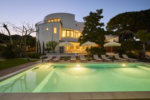 Casa Redonda villa at dusk with illuminated pool, lounge chairs, and modern architecture in Aroeira