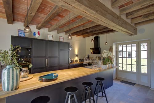 Cuisine moderne du Cloffy B&B à Nouans-les-Fontaines avec poutres apparentes, mobilier noir et îlot en bois.