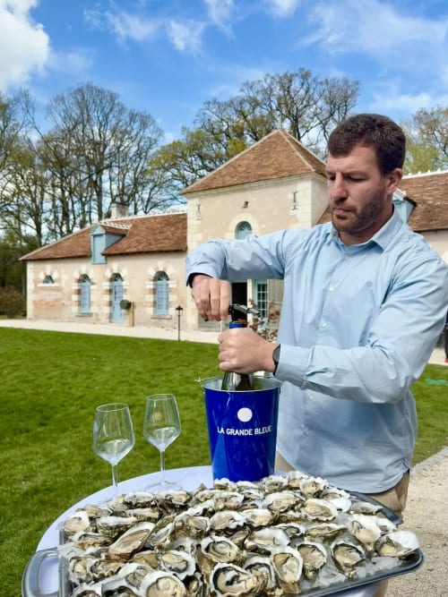 Homme ouvrant une bouteille de champagne avec des huîtres fraîches au Cloffy B&B à Nouans-les-Fontaines, France