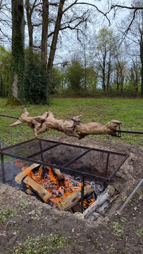 Installation de grill sur feu de camp à la Cloffy B&B à Nouans-les-Fontaines, France avec broche rustique en bois et paysage forestier