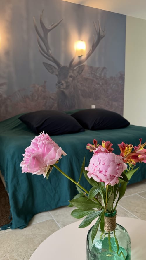 Pivoines roses dans un vase sur le lit avec fresque de cerfs, chambre La Forêt à La Cloffy B&B, Nouans-les-Fontaines