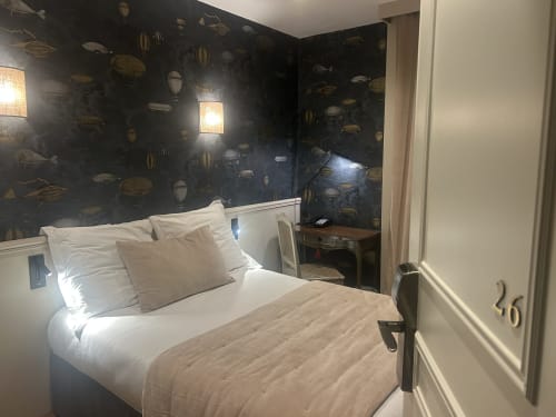 Chambre Supérieure de l'Hôtel des Bains avec lit, papier peint à motifs sombres et vue sur la ville