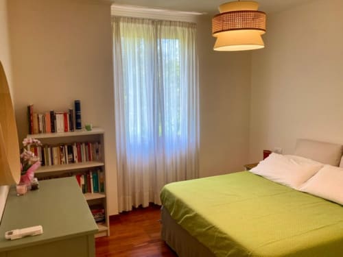 Camera luminosa a Crawford Home Sant'Agnello con letto matrimoniale, biancheria verde lime, pavimento in legno, libreria, scrivania e giardino