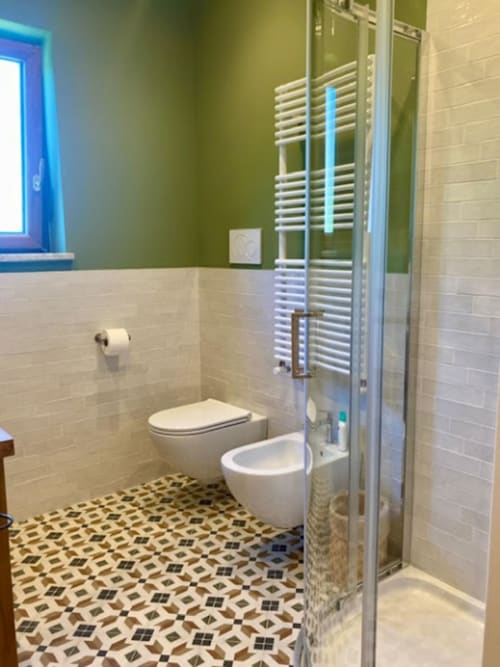 Bagno moderno nell'appartamento Crawford Home con toilette, bidet, doccia walk-in, scaldasalviette e pavimento con piastrelle geometriche