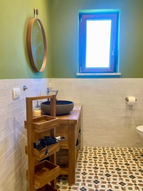 Bagno moderno con mobile in legno, lavabo rotondo, finestra con telaio blu e pavimento con piastrelle geometriche a Crawford Home,