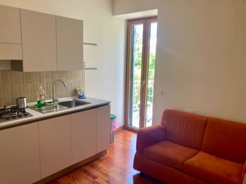 Cucina moderna e zona living nell'appartamento Crawford Home di Sant'Agnello, con divano rosso e porte con vista sul giardino