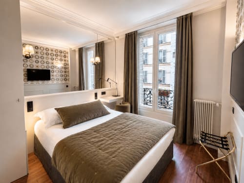 Chambre confortable de l'Hôtel des Bains avec lit queen-size, vue sur la ville, rideaux taupe et décoration moderne