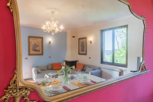Elegante sala da pranzo dell'hotel Prince Garda a Salò riflessa in uno specchio dorato ornamentale, con tavolo apparecchiato e zona living