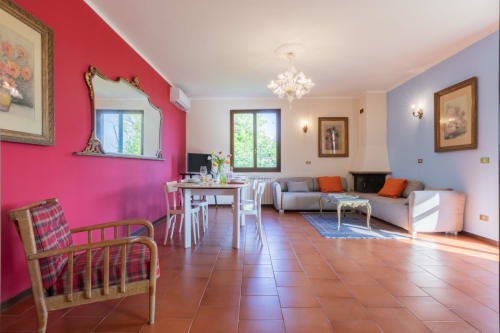 Zona giorno open-plan dell'Hotel Prince Garda a Salò con parete accent rosa, pavimenti in terracotta e arredamenti moderni