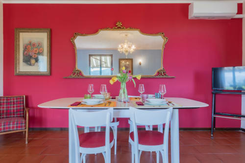 Sala da pranzo Prince Garda a Salò con pareti rosa, tavolo elegantemente apparecchiato, specchio ornato e sedie bianche