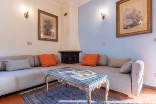 Elegante soggiorno dell'hotel Prince Garda a Salò con divano grigio a forma di L, tavolino da caffè ornamentale e opere d'arte floreali
