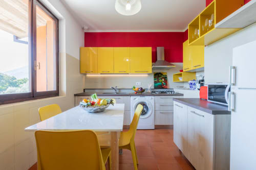 Cucina moderna dell'hotel Prince Garda a Salò con mobili gialli, parete rossa di accento e zona pranzo