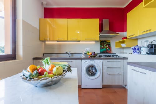Cucina moderna dell'Hotel Prince Garda a Salò con armadi gialli, pareti rosse e prodotti freschi sul bancone