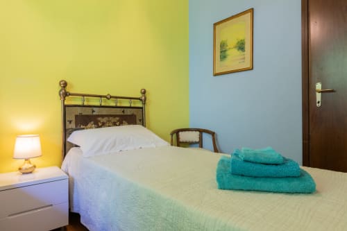 Camera luminosa dell'Hotel Prince Garda a Salò con pareti gialle e blu, letto singolo, asciugamani turchesi e lampada da comodino