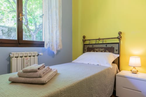 Camera luminosa al Prince Garda hotel di Salò con pareti gialle, letto in ferro e asciugamani piegati