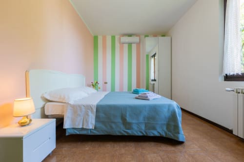 Luminosa camera da letto all'hotel Prince Garda di Salò con biancheria blu, parete a righe e arredi moderni