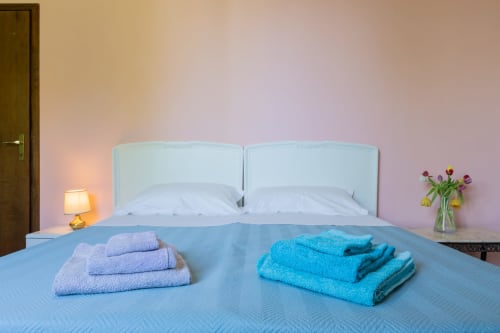 Camera moderna dell'Hotel Prince Garda di Salò con biancheria azzurra, cuscini bianchi, asciugamani freschi e fiori sul comodino