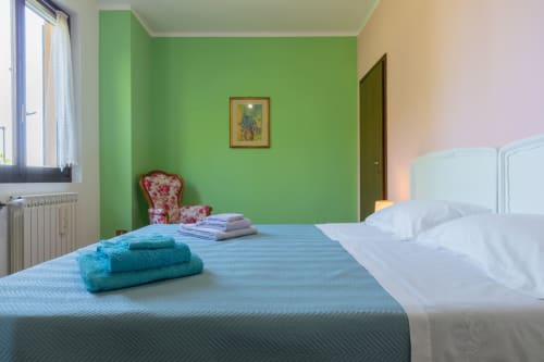 Luminosa camera d'hotel Prince Garda a Salò con pareti verdi, letti gemelli, asciugamani turchesi e arredamento moderno