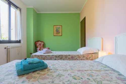 Camera luminosa dell'hotel Prince Garda a Salò con pareti verdi, due letti e asciugamani turchesi