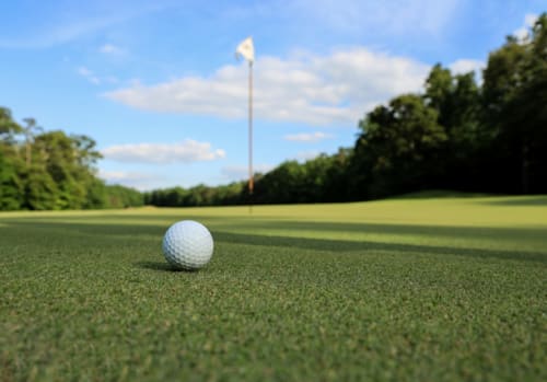 Golf ball on putting green with flagstick at Hotel de la Font Perelada in Girona, Spain