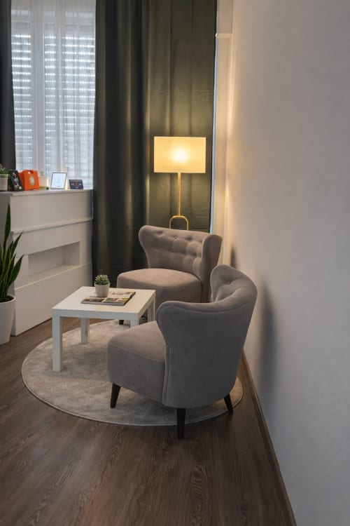 Moderna zona lounge con due poltrone grigie, tavolino bianco e lampada da terra presso l'hotel boutique Vatican Living Rome a Roma